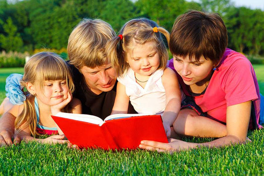 Children and parents reading book in park summer break learning