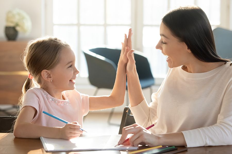 Mom high-fiving daughter homeschooling with positive reinforcement