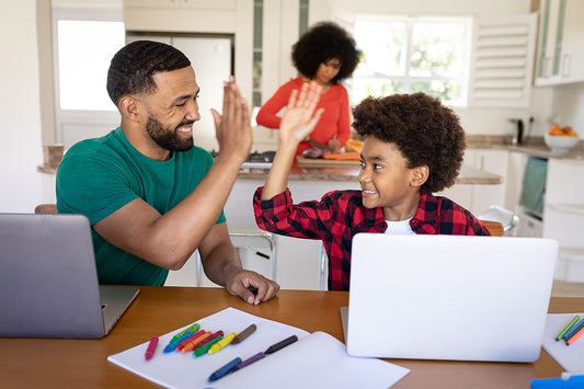 Dad high-fiving son for school achievement. Define success in homeschooling.