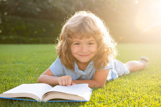 Child in field reading book homeschool through the summer