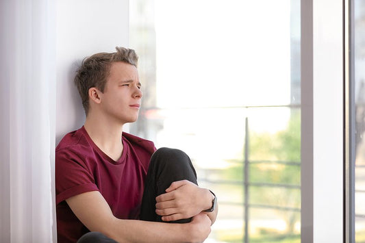 Teenager depressed looking out window alone struggling with mental health