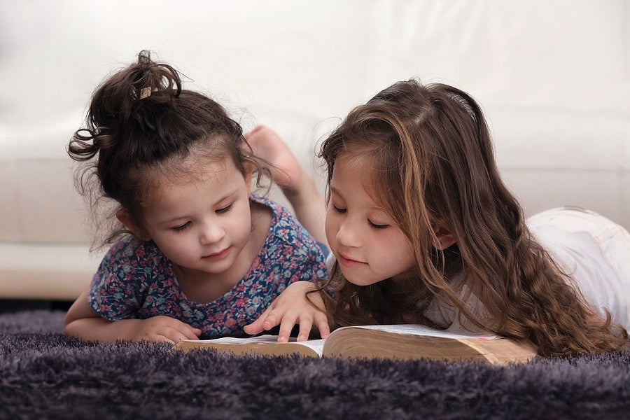 Two young kids read the Bible, representing family Bible memorization.